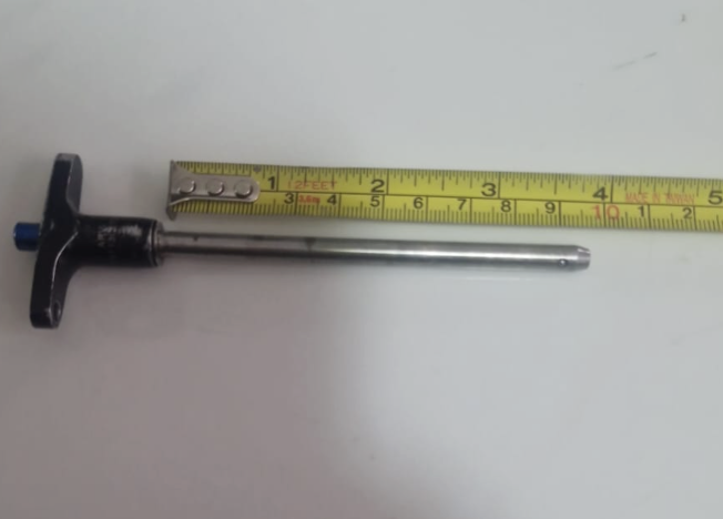 A person measuring a hole in a metal plate with calipers